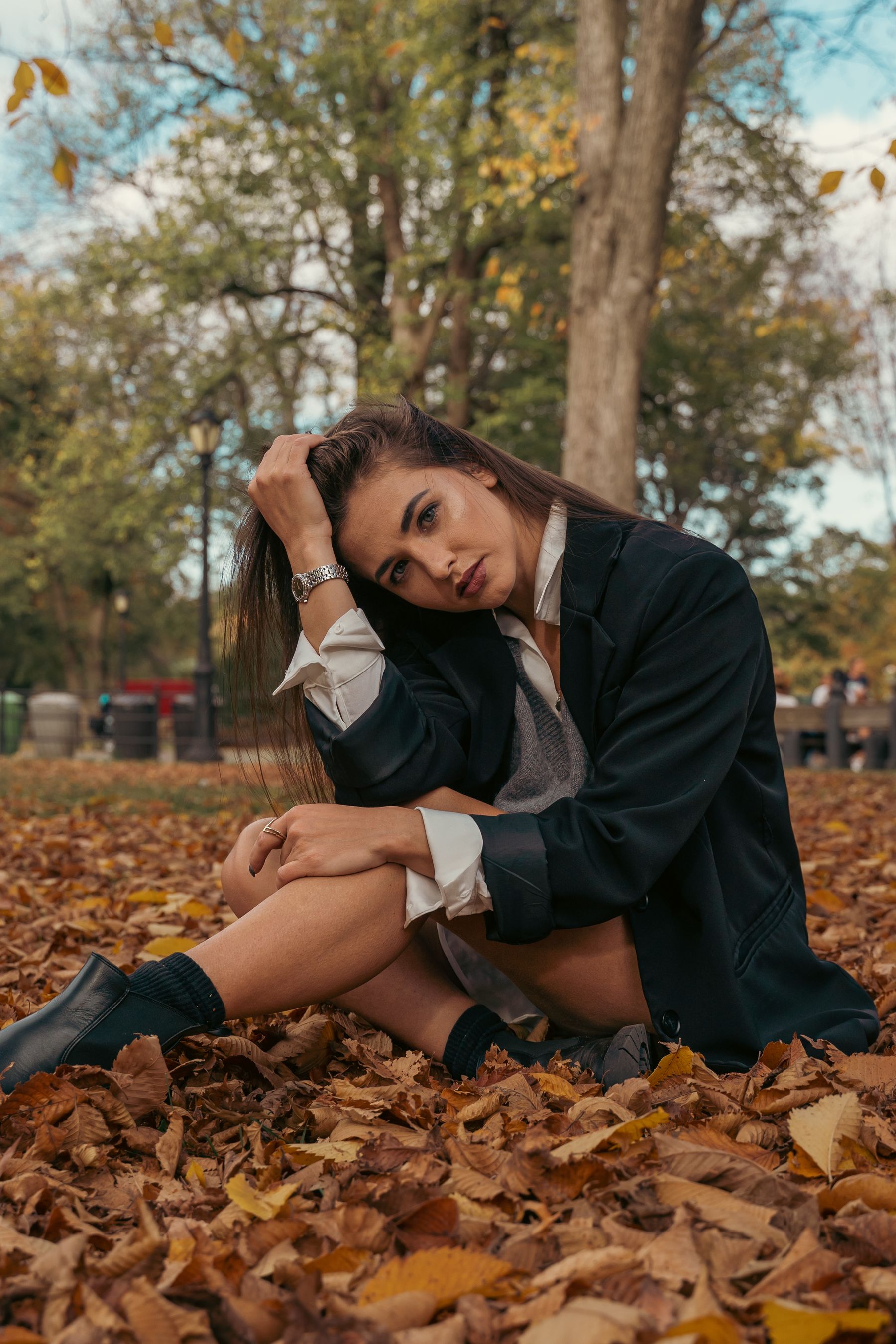 Black ankle boots worn with a blazer among autumn leaves